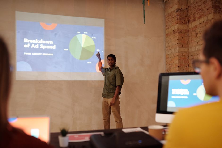 ai ad generators — Young man delivering a business presentation on ad spend with charts and graphs in a modern office se