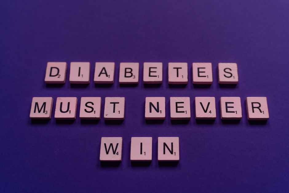 hepatitis elimination — Scrabble tiles spelling 'Diabetes must never win' on a purple background for awareness.