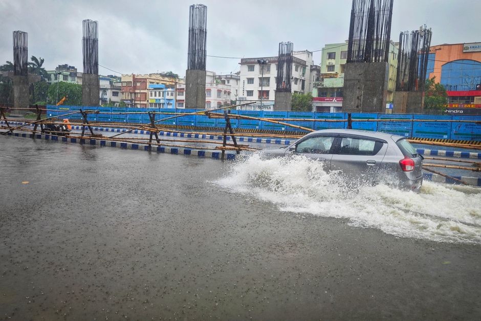 imd rain alert — A car navigates a flooded street in Kolkata, India after heavy rain, showcasing urban challenges.