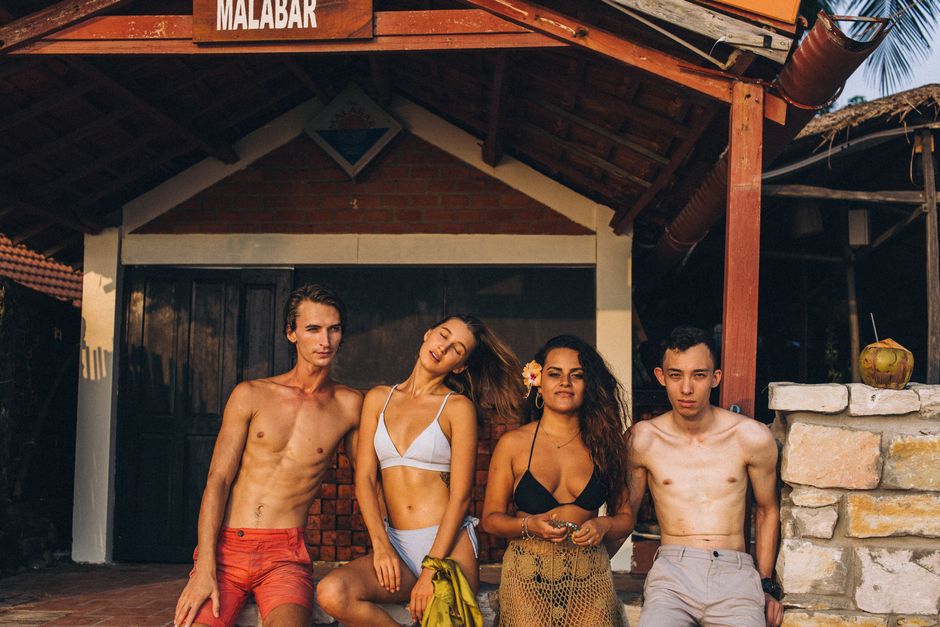 malabar gold dhoni — Four friends enjoying a sunny day at a rustic beachside hut, perfect for lifestyle ads.