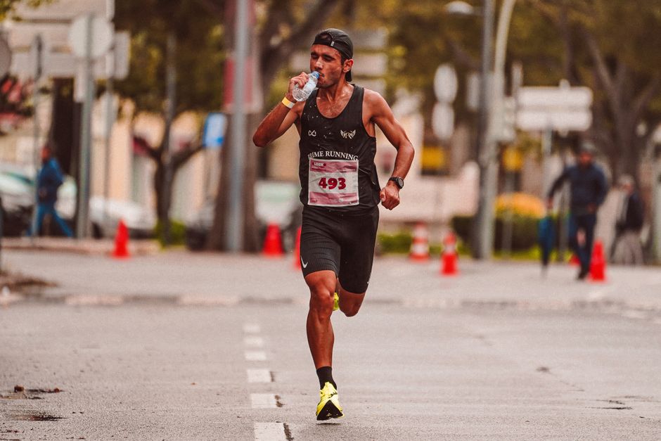 ors for diarrhea — Athlete running in a marathon, staying hydrated. Outdoor city street scene.