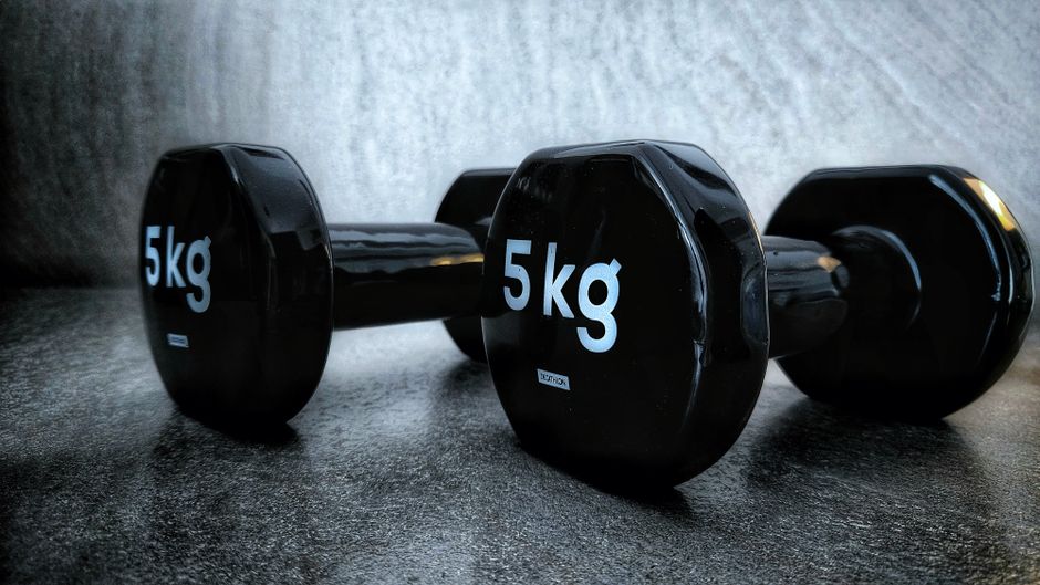 sanju samson lifestyle — Close-up of black 5kg dumbbells on a textured dark surface, highlighting fitness and strength t