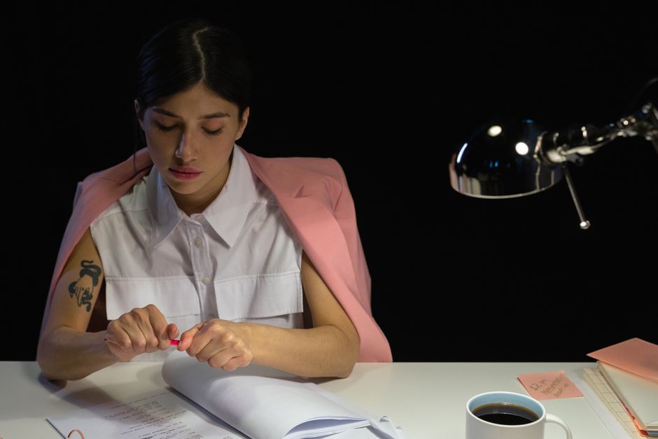 venus in virgo — Young woman focused on paperwork at night, emphasizing dedication and professionalism.