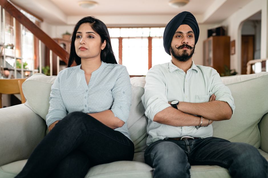 vip culture india — Resentful young Indian couple ignoring each other while sitting on couch together with crossed arms